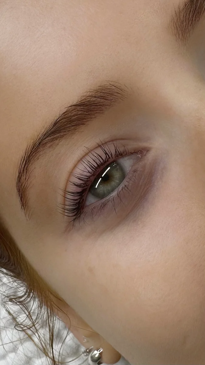 Side detail of curled natural lashes and a softly shaped brow